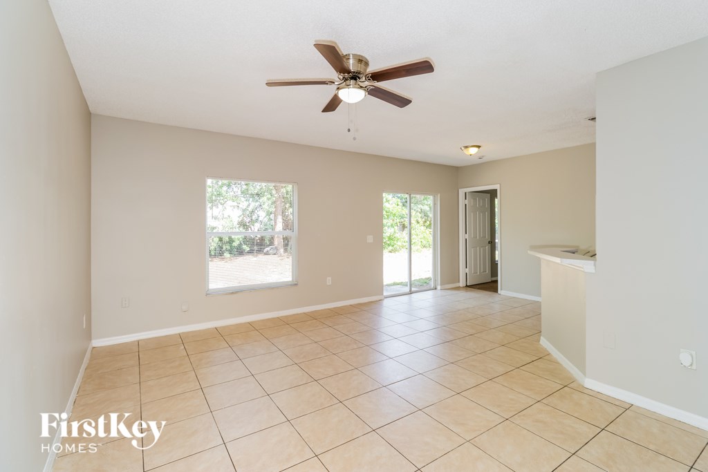 A spacious room with a ceiling fan and tiled flooring.