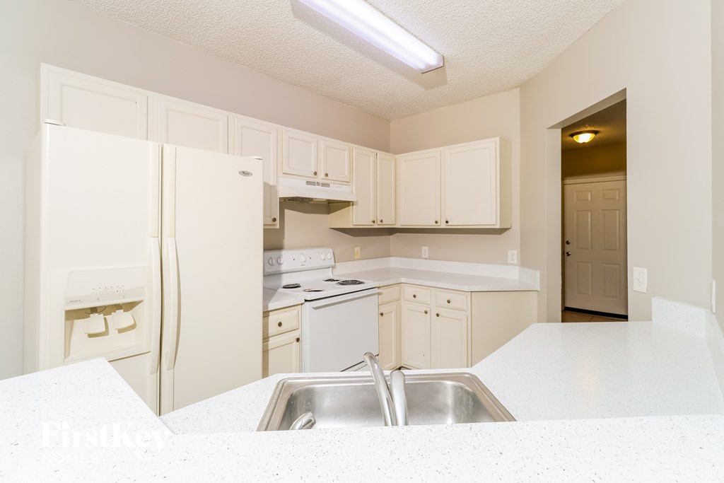 A kitchen with white appliances and cabinets.