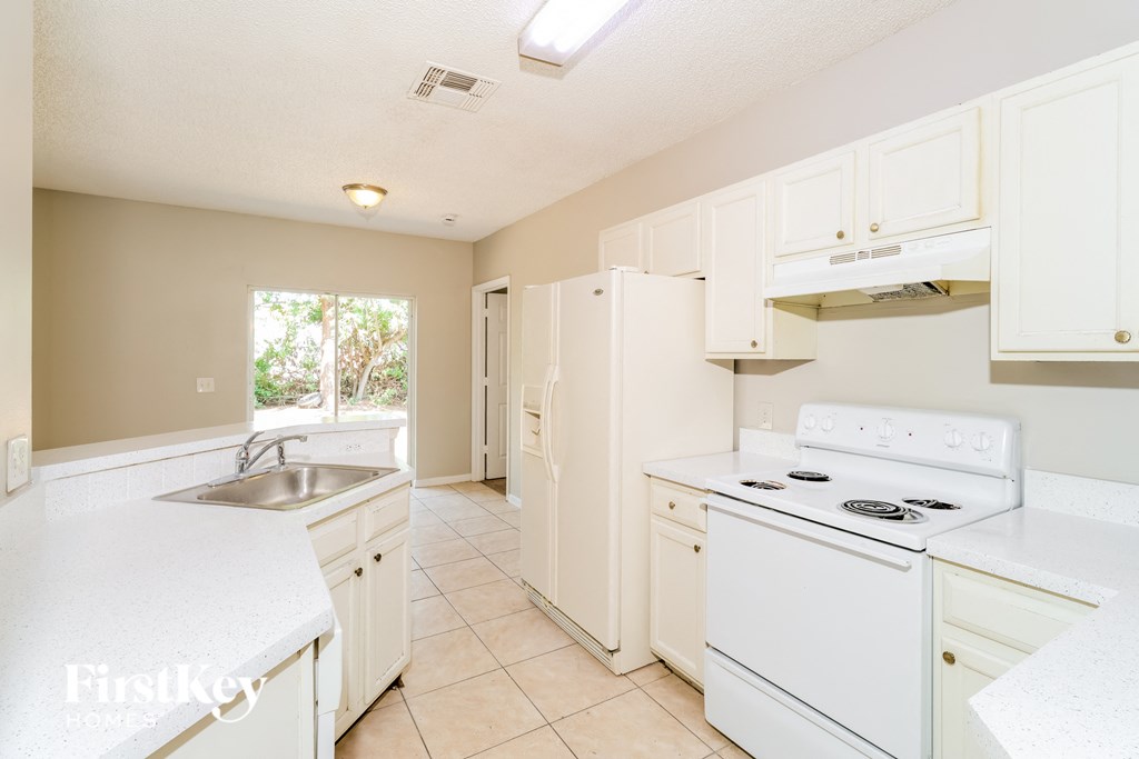 A kitchen with white appliances and cabinets.