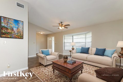 A living room with a couch, a coffee table, and a painting on the wall.
