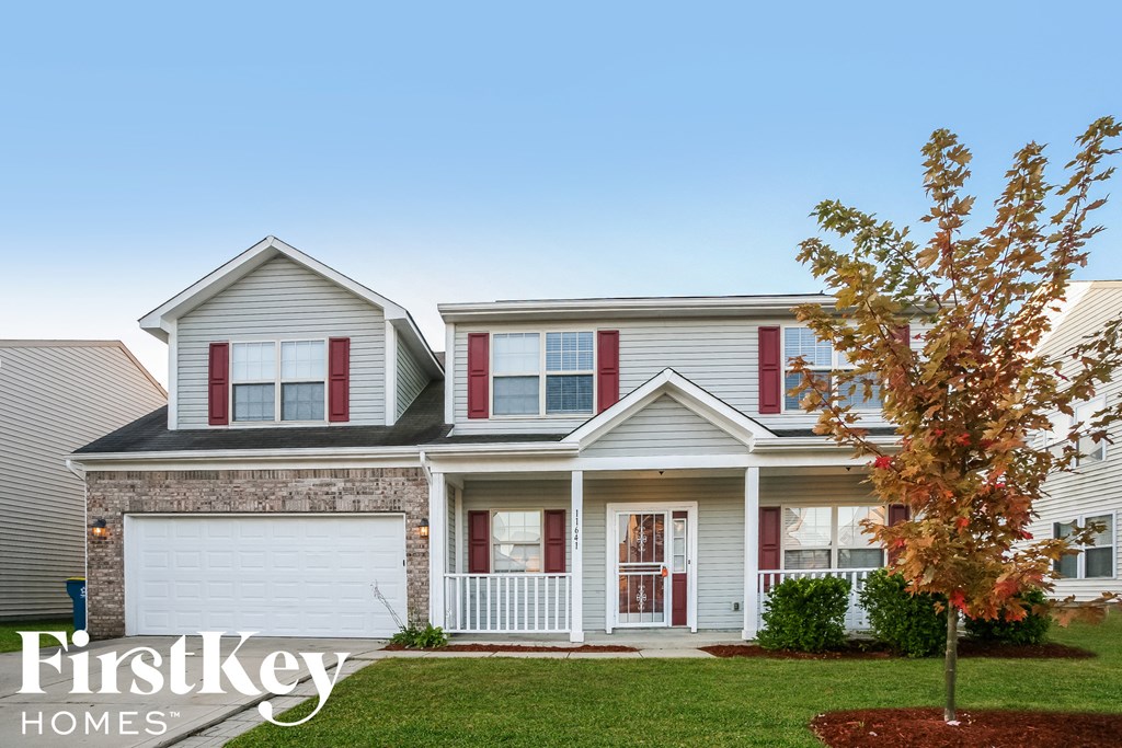 a white house with red shutters and a tree in the yard
