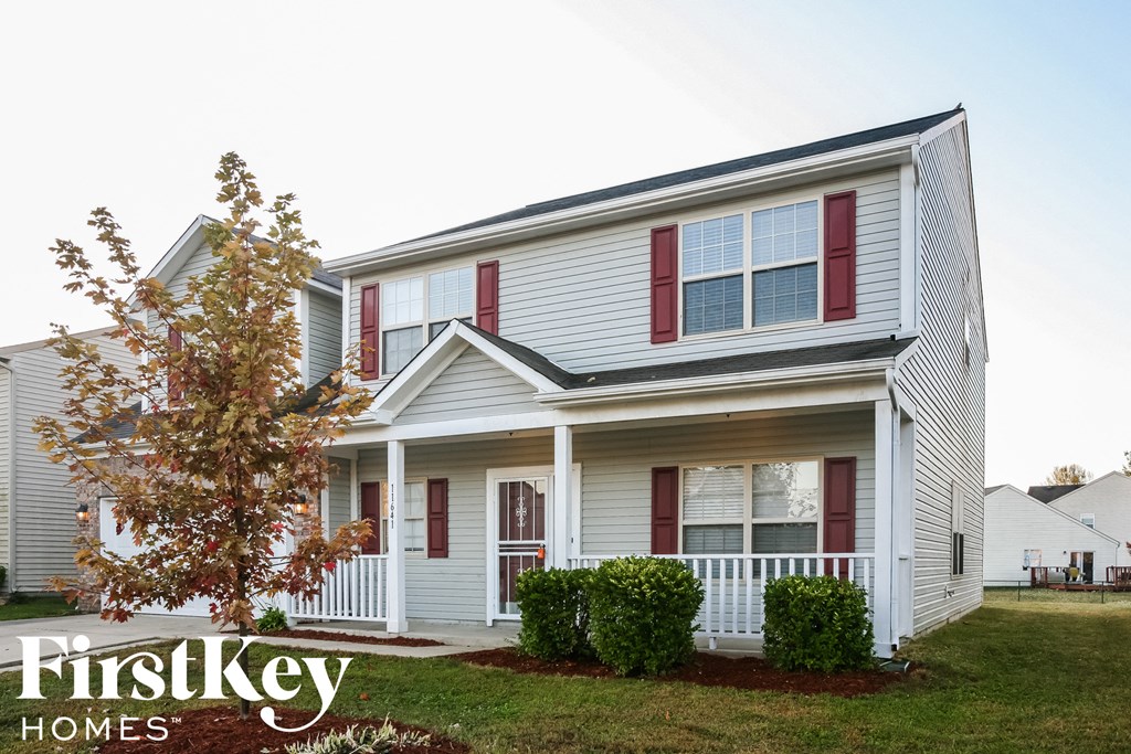 a white house with red shutters and a lawn