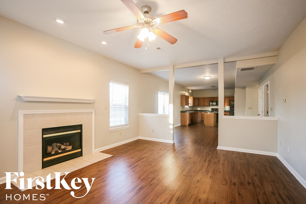 an empty living room with a fireplace and a ceiling fan