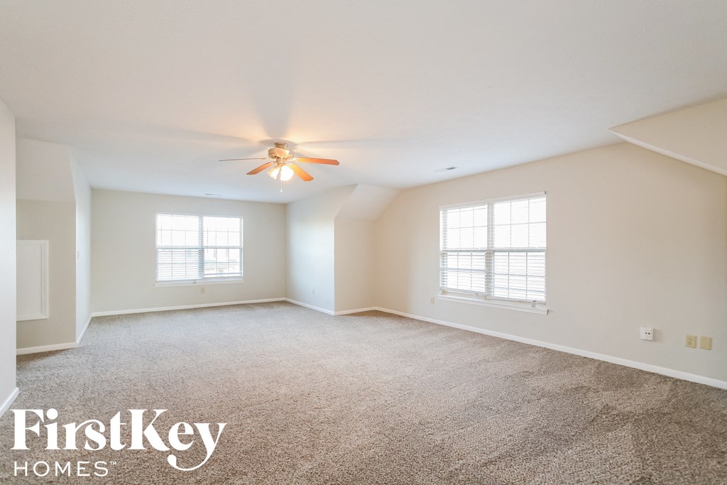 a spacious living room with carpet and a ceiling fan