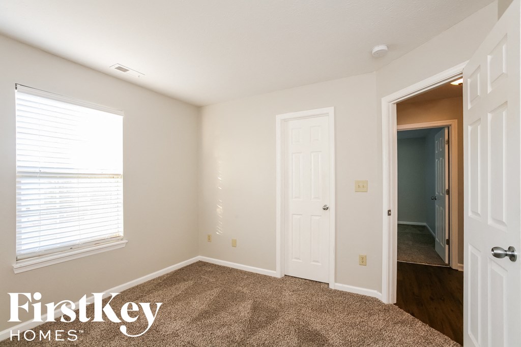 a bedroom with a door to a hallway and a window