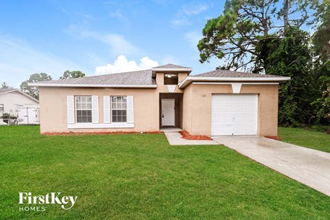 A beige house with a white garage door and a driveway leading to it.