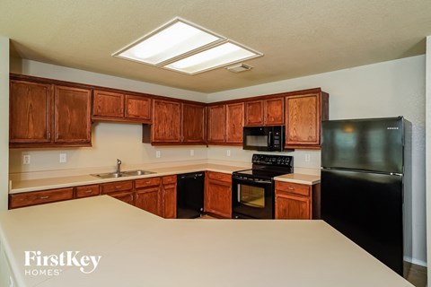 a kitchen with wooden cabinets and black appliances and a white counter top