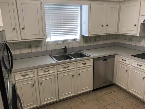 A kitchen with white cabinets and a black fridge.
