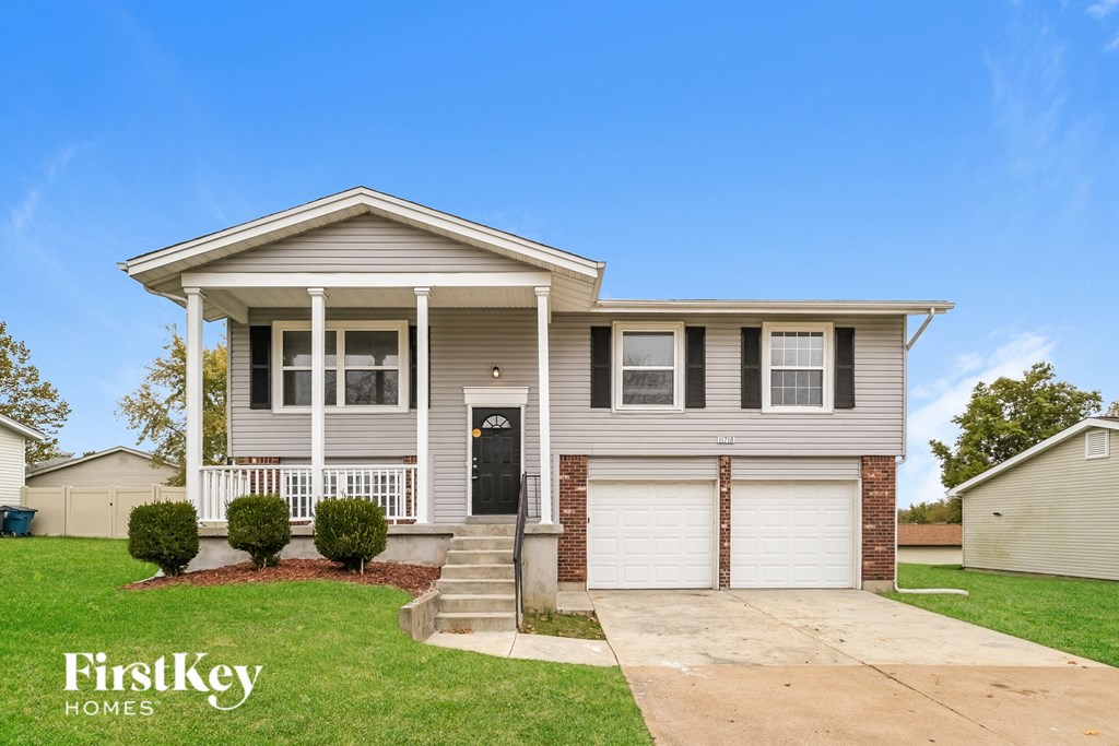 a beige house with a black door and a lawn