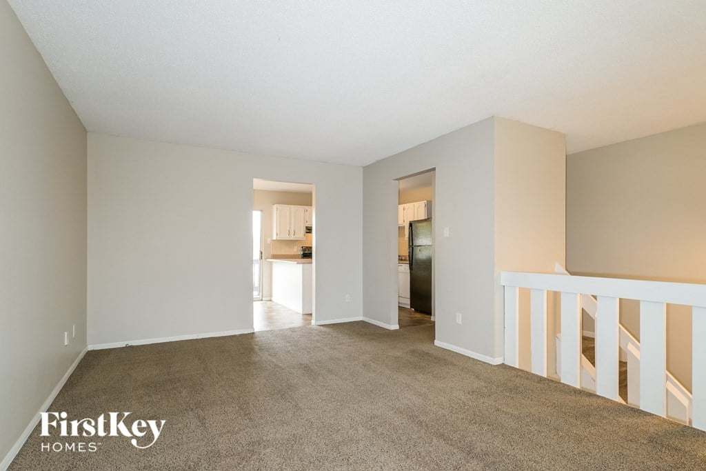 a living room with a carpeted floor and a staircase