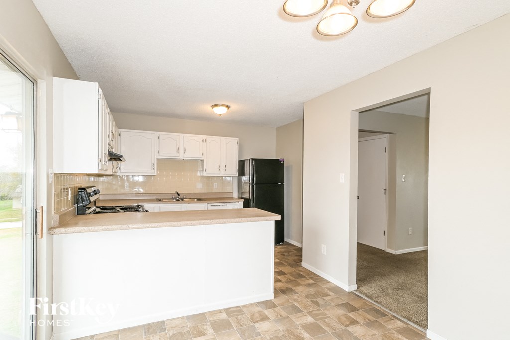 a kitchen with white cabinets and a black refrigerator