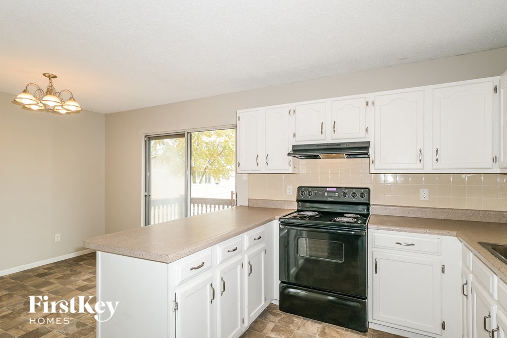a kitchen with white cabinets and a black stove and oven