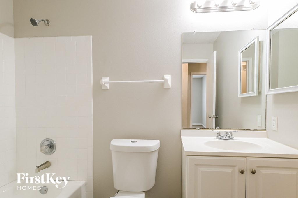 a white bathroom with a toilet sink and mirror