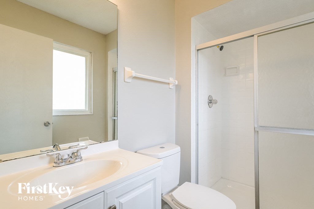 a white bathroom with a shower toilet and sink