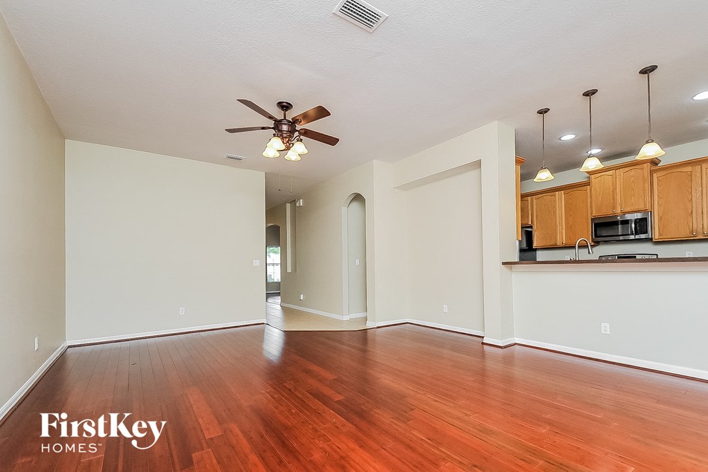 an empty living room with wood flooring and a ceiling fan