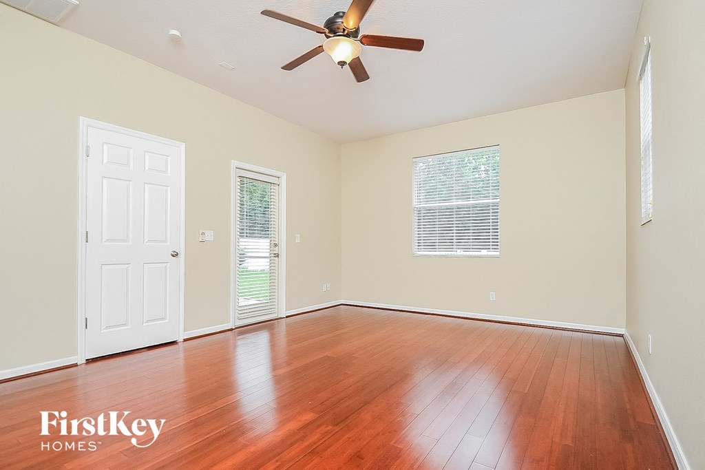 an empty living room with wood floors and a ceiling fan