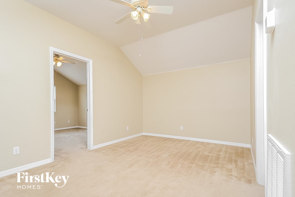 a spacious living room with beige walls and a ceiling fan