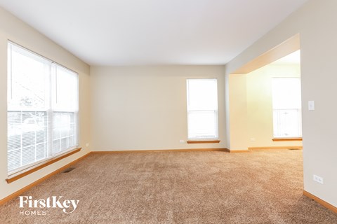 a spacious living room with two windows and carpeting