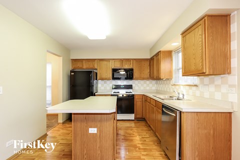 a kitchen with wooden cabinets and black appliances and a white counter top