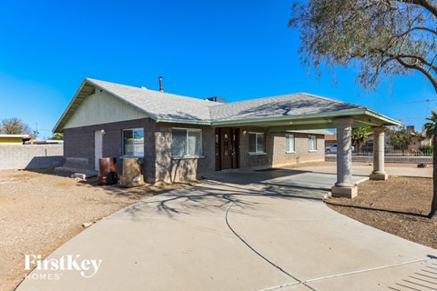A house with a grey roof and a white fence is for sale.