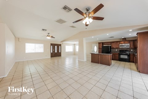 A spacious living room with a kitchen in the background.
