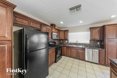 A black refrigerator in a kitchen with wooden cabinets.