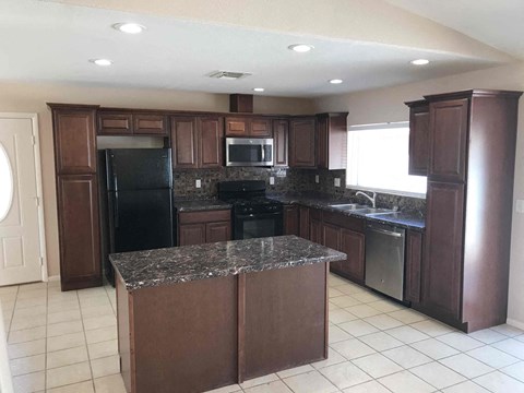 A kitchen with dark wood cabinets and a granite countertop.