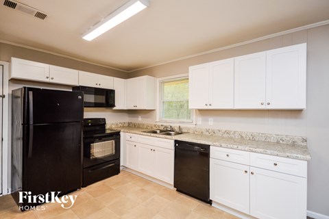 a kitchen with white cabinets and black appliances