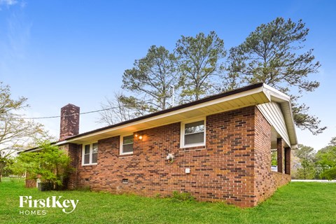 a brick house on a green lawn with trees