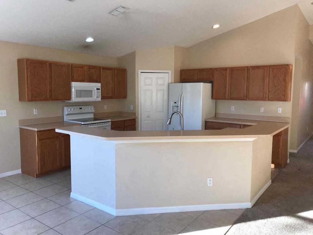A kitchen with brown cabinets and a white refrigerator.