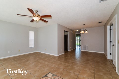 A spacious room with a ceiling fan and a rug on the floor.
