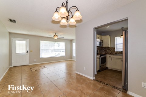 A spacious living room with a kitchen in the background.