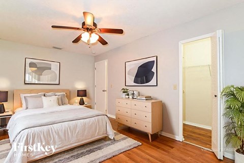 A bedroom with a bed, dresser, and ceiling fan.