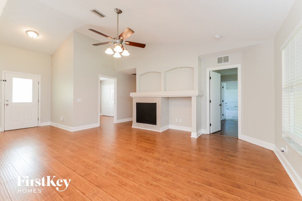 A spacious living room with a fireplace and a ceiling fan.