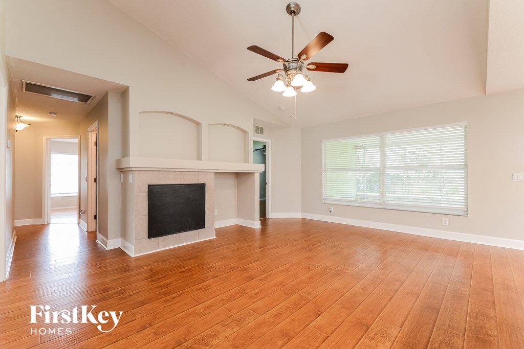 A spacious living room with a fireplace and a ceiling fan.