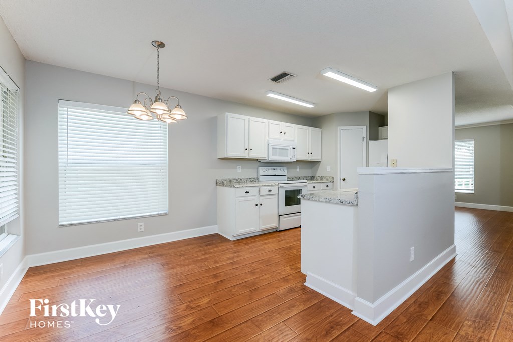 A kitchen with wooden floors and white appliances.