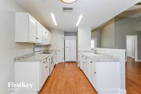 A kitchen with white cabinets and a marble countertop.