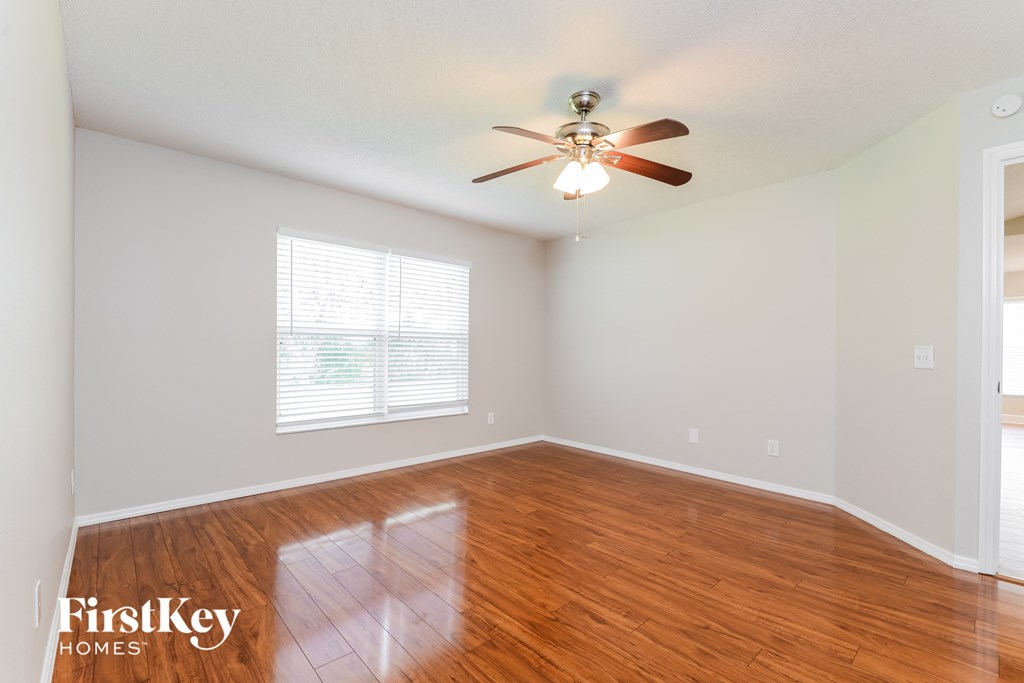 A room with a ceiling fan and wooden flooring.