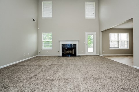 the spacious living room with a fireplace and carpeted flooring