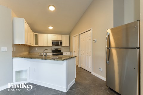 A kitchen with a stainless steel refrigerator and white cabinets.