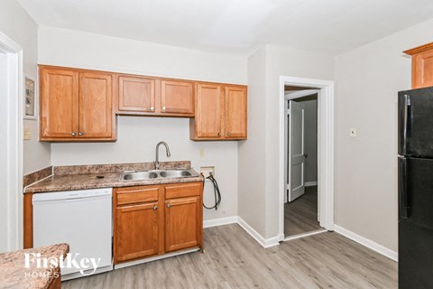 A kitchen with wooden cabinets and a black fridge.