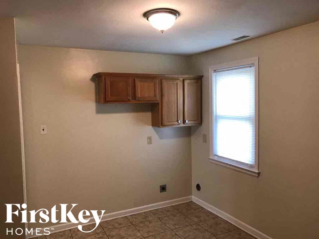 A room with a window and a wooden cabinet above it.