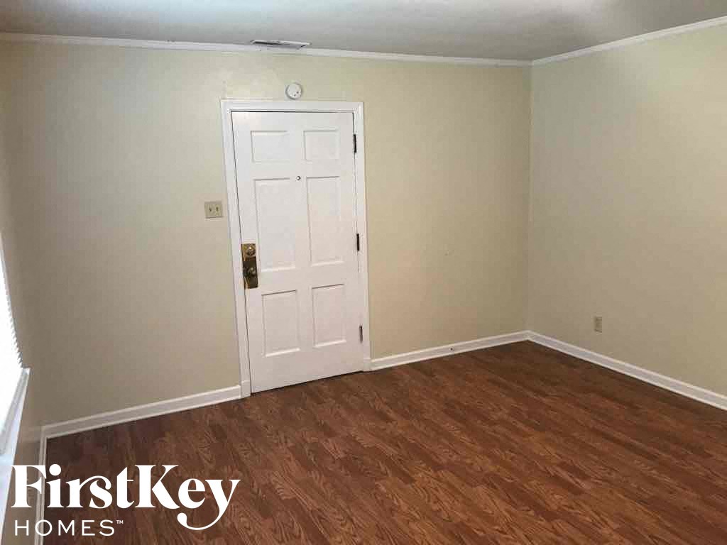 A room with a white door and wooden flooring.