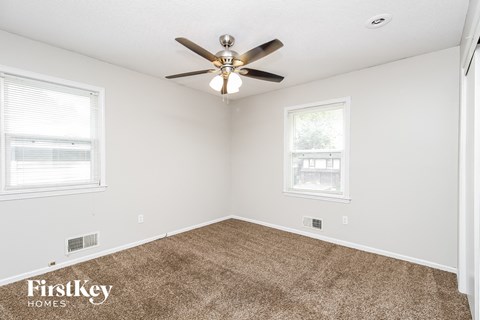 the living room of a home with carpet and a ceiling fan
