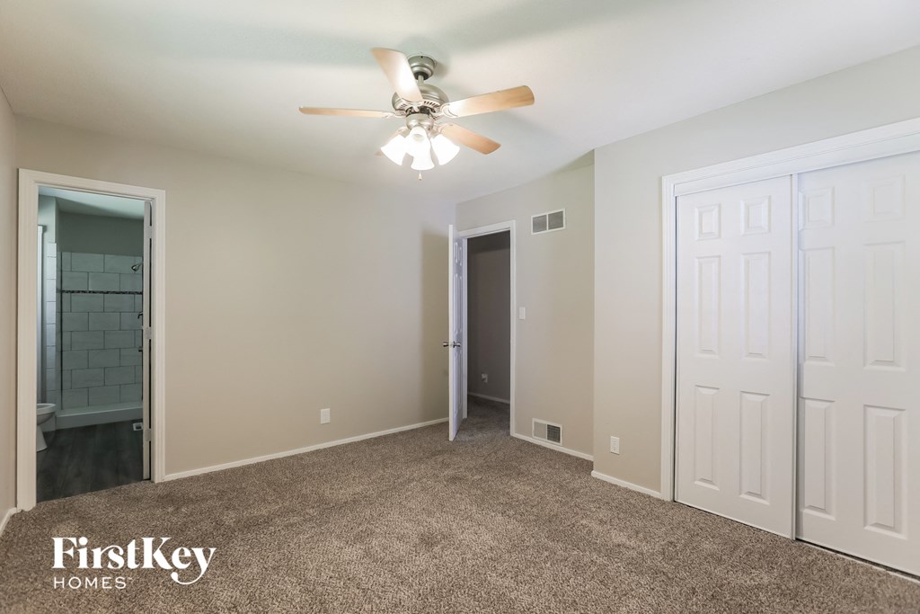 A spacious room with a ceiling fan and a carpeted floor.