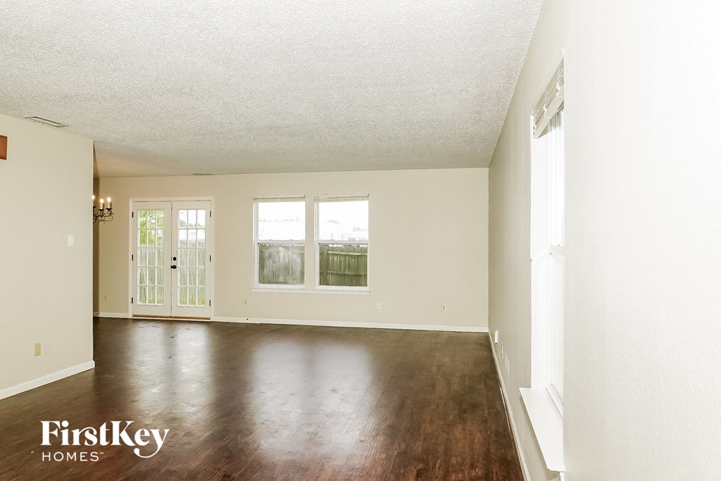 an empty living room with wood floors and white walls