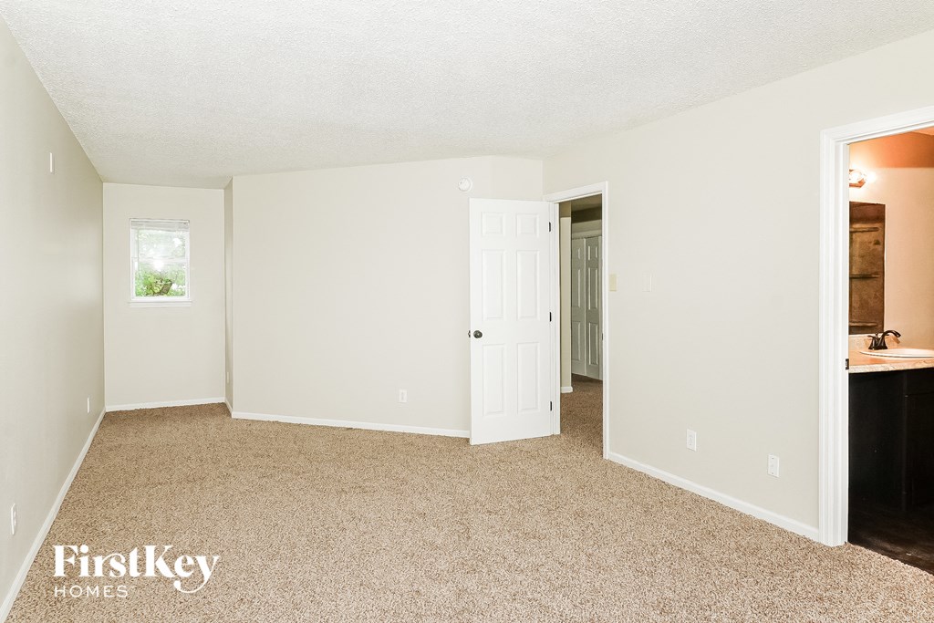 a bedroom with a door to a bathroom and a sink