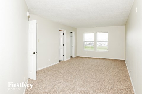 a spacious living room with white walls and carpet