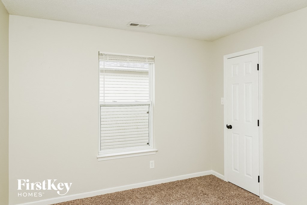 a bedroom with white walls and a white door and a window