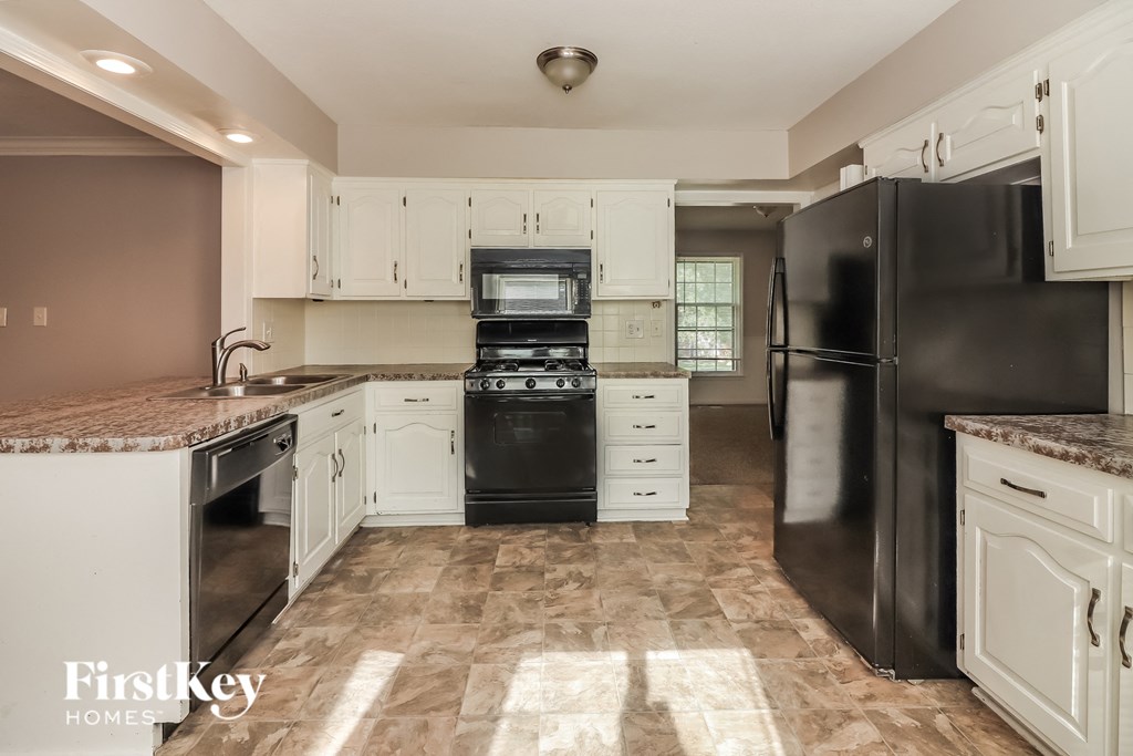 a kitchen with white cabinets and black appliances